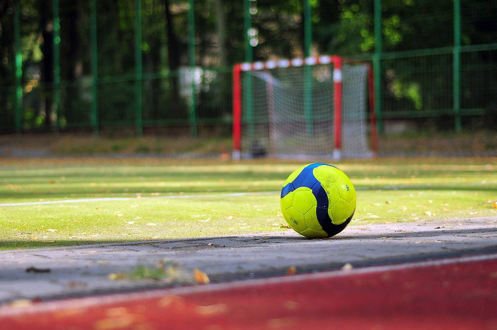 Ball vor einem Fußballplatz mit einem Tor im Hintergrund
