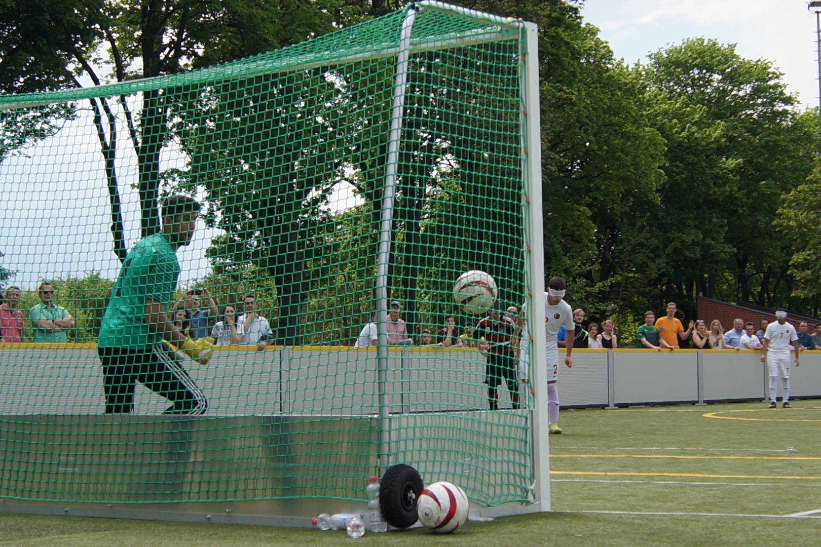 Zu sehen inst ein Blindenfußball ca. 1 Meter über dem Bodem. Das Foto ist hinter dem Tor aufgenommen wurden. Ob der Ball hinter, oder vor der Torlinie ist, lässt sich nur schwer beurteilen