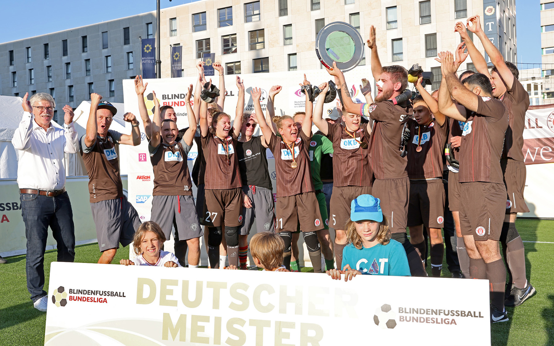 Der FC St. Pauli wurde Meister 2024 Blindenfußball-Meister und durfte die Schale in Darmstadt Richtung Himmel recken. Auf dem Foto stehen die Spieler bei der Übergabe des Pokals zusammen, Kapitän Philipp Versen hält die Schale hoch und wird von seinen Mitspielern bejubelt. Foto: Carsten Kobow